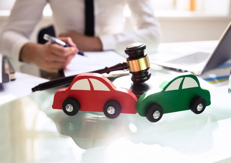 Gavel on table next to 2 toy cars